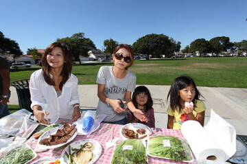 Two families enjoying BBQ in the park