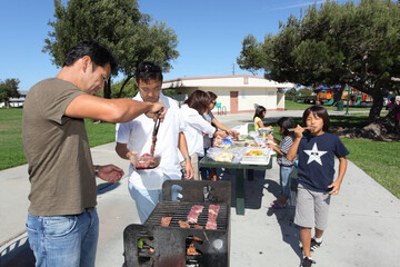 Two families enjoying BBQ in the park