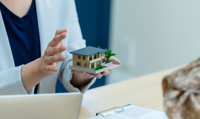 住宅模型を持って説明する女性担当者
