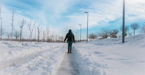 woman with her back turned walking across a snow-covered street