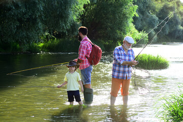 I love fishing. Senior man fishing with son and grandson. Grandfather, father and son are fly fishing on river.