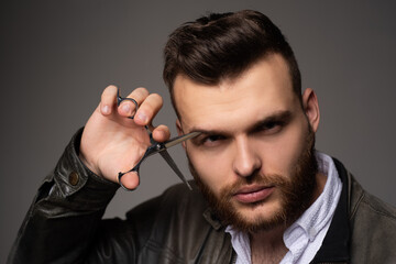 Young sexy man, portrait of guy with barber scissors for barber shop. Modern barbershop, shaving. Handsome male with modern hairstyle on black.