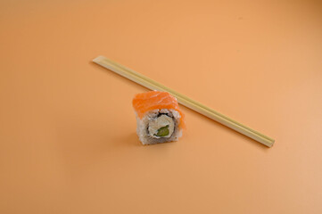 Close-up of a piece of philadelphia sushi with chopsticks