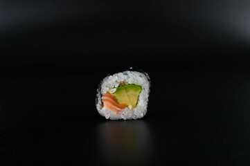 Close-up of a piece of sushi on black background.