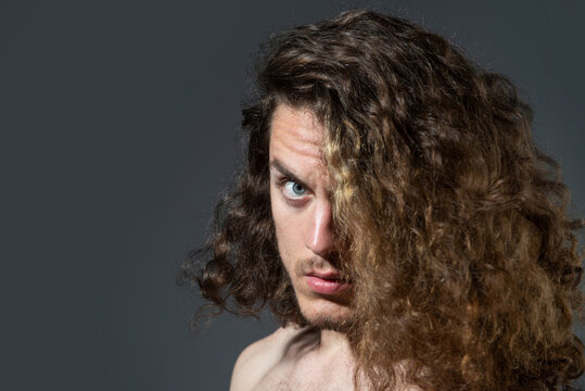 Closeup portrait of male model with long curly hair. Healthcare and hair care concept.