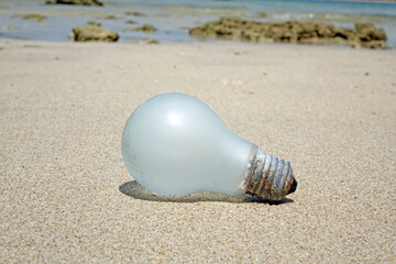 Light bulb on the beach. Sea beach pollution. Selective focus with copy space