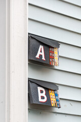The exterior of a light green clapboard siding wall with a white door and trim, and two black metal...