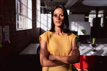 Portrait of caucasian businesswoman standing in sunny office looking to camera, with shadow on face