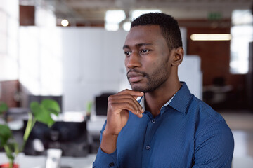 Thoughtful african american businessman standing in office looking away