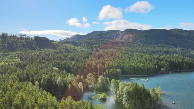 Beautiful cinematic scenery, lush green rainforest on lake and perfect clouds over foresty mountains aerial drone shot in Lake Cushman Hoodsport Mason County Washington State Pacific Northwest