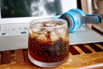 Cola drink with ice cubes and notebook with  headphone work from home concept
