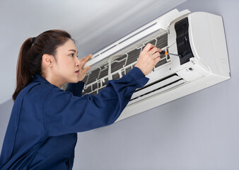 Fototapeta na wymiar female technician service using screwdriver to repairing air conditioner indoors