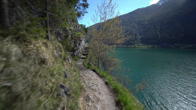 Hiking trail along a beautiful lake in Austrian Alps. Footpath in mountains by water.