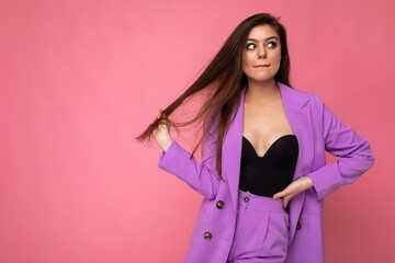 Portrait of thoughtful beautiful fashionable brunette woman in casual trendy violet jacket isolated on pink background with free space