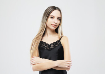 Beautiful young woman in black nightgown posing on white background