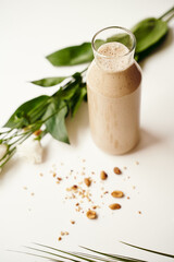 american raw vegan smoothie with peanuts , cashew milk, himalayan salt, cinnamon, banana, date and beautiful flower. glass of smoothie