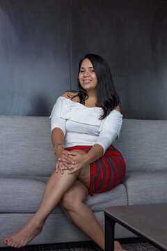 Young latin woman poses for some portraits taken from the couch at home dressed in casual clothes. Home photoshoot concept