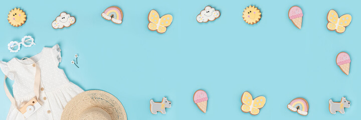 Summer banner made with white dress, the straw hat, sunglasses and funny gingerbread on blue background. Fashion girl lookbook concept. Top view Flat lay Copy space