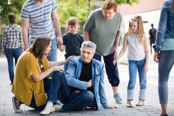 Fototapeta premium People of different ages helping mature man with pain in heart in park