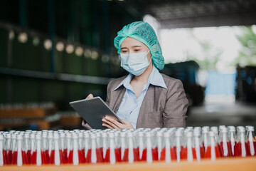 Female Inventory Manager with labtop is checking juice bottles before shipment. Inspection quality...