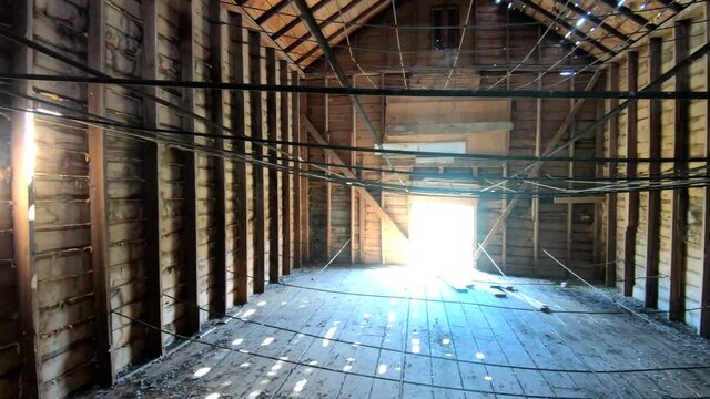 Inside on an old wooden barn in the Country on a sunny day with light coming through the windows.