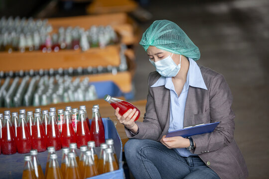 Female Inventory Manager Shows Digital Tablet checking juice bottles before shipment. Inspection quality control. Manager inspecting production line at drinks production factory