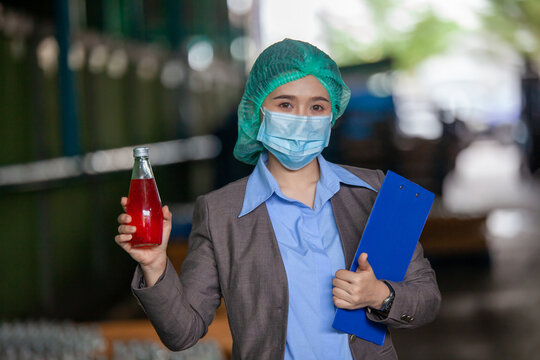 Female Inventory Manager Shows Digital Tablet checking juice bottles before shipment. Inspection quality control. Manager inspecting production line at drinks production factory