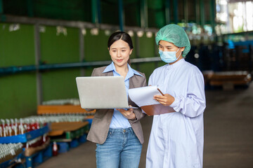 Young female manager and workers in bottling factory checking products before shipment. Inspection quality control. Manager  inspecting production line at drinks production factory
