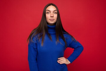 Young calm serious beautiful brunette woman with sincere emotions isolated on background wall with copy space wearing casual trendy blue sweater