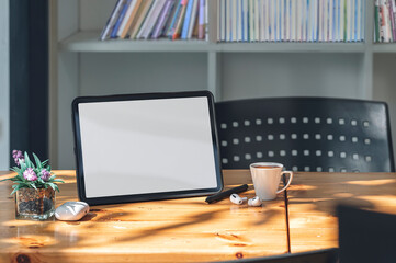 Mockup blank screen tablet and gadget on wooden table in living room with morning sunlight.