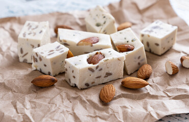 Walnut halva with almonds and sunflower seeds on brown craft paper. Traditional oriental dessert.
