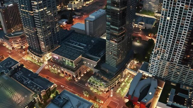 Cinematic 4K night bird's-eye footage of the city center of Bellevue, retail stores, Bellevue Square, illuminated skyscrapers, tall office and apartment buildings during blue hour after sunset