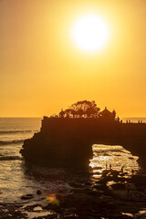 Silhouette of Pura Batu Bolong in golden sunset it the traditional Balinese temple located on a rocky, in the Tanah Lot area, Bali, Indonesia.