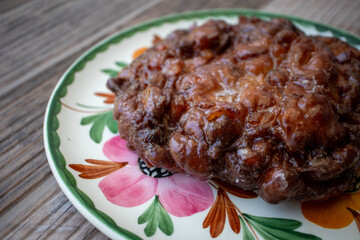 An apple fritter pastry for breakfast on a plate at the donut shop
