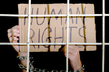 concept human rights freedom of speech hands shackled with an iron chain hold a cardboard sign with...