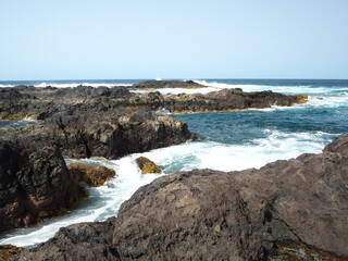 Fototapeta na wymiar Volcanic coast of the Atlantic Ocean. Waves crash against black rocks. Tenerife, Canary Islands 