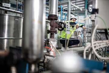 Engineer in uniform holding a tablet in her hands and conducting an inspection at the machine in Factory. Industrial production concept