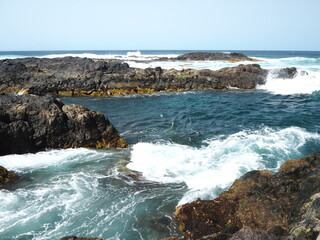 Volcanic coast of the Atlantic Ocean. Waves crash against black rocks. Tenerife, Canary Islands 