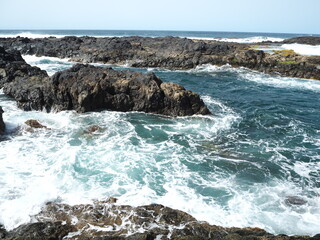 Volcanic coast of the Atlantic Ocean. Waves crash against black rocks. Tenerife, Canary Islands 