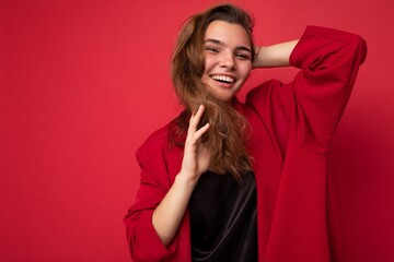 Young beautiful european stylish brunette woman wearing black blouse top and red cardigan isolated over red background with positive sincere emotions. Simple and natural looking at the camera. Free