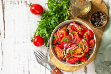 Summer snack or lunch. Fresh tomato salad with onions, herbs and olive oil on a white wooden table. Top view flat lay background. Copy space.