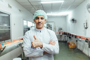Obraz premium worker thumbs up in production line at drinks production factory backgrou