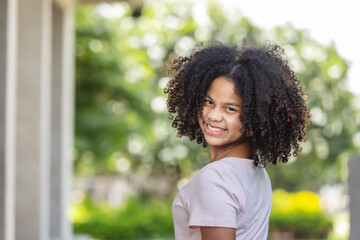 portrait of African American curly hair girl  smiling with happiness and looking at camera.Nature background.