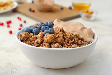 Bowl with tasty granola on grunge background