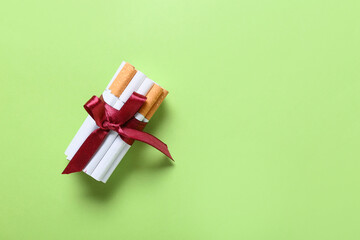 Cigarettes tied with ribbon on color background. Concept of addiction