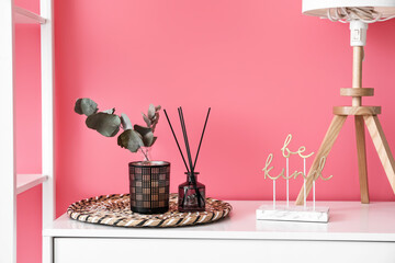 Reed diffuser with candle on shelf near color wall