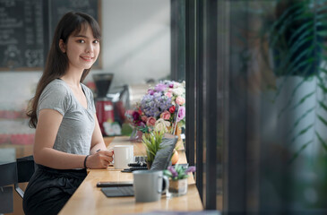 Pretty woman in casual wear holding mug sitting at counter table in co-workspace with happiness.