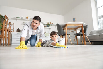 Father and son cleaning floor in kitchen