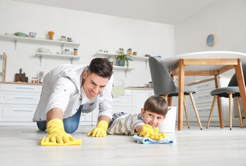 Father and son cleaning floor in kitchen