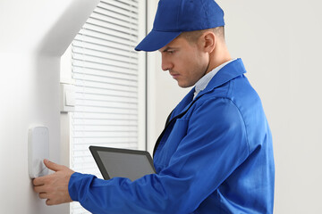 Worker with tablet computer checking alarm system indoors
